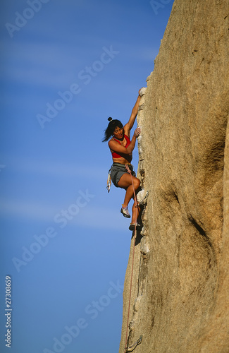 Female climber clinging to a cliff.