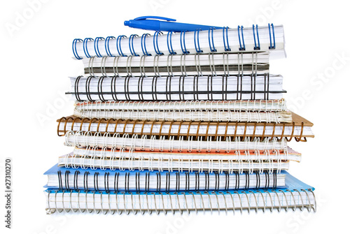 Stack of spiral notebooks with a blue pen
