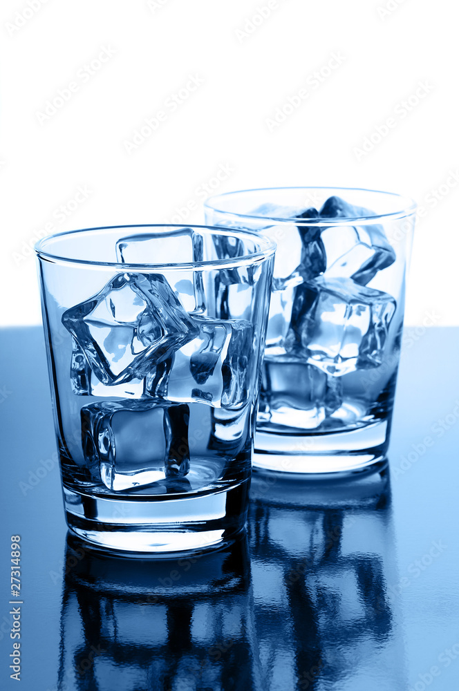 Glasses with crystal clear ice cubes on glossy background Glasses with crystal clear ice cubes on glossy background