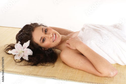 Portrait of a young brunette woman lying on a bamboo mat
