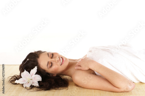 Portrait of a young brunette woman lying on a bamboo mat