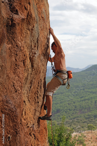 Rock climber on the cliff with mountainous background