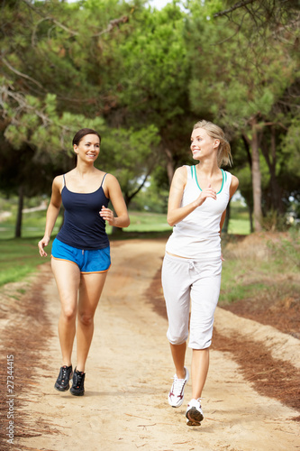 Two young women running in park