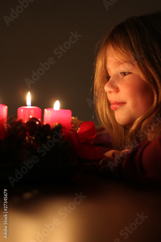 Mädchen schaut auf Adventskranz photo