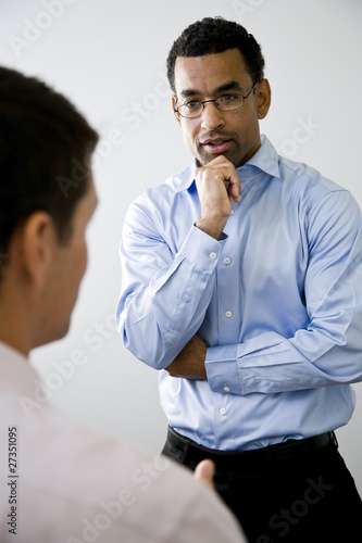 Mid-adult office worker listening to colleague