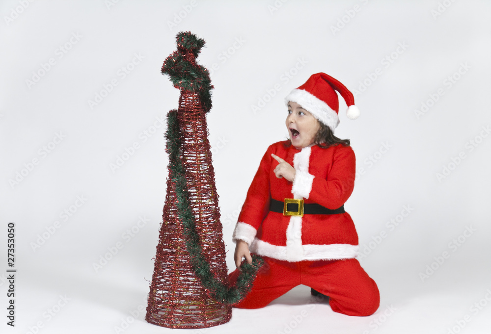 niña vestida de papa noel señalando arbol de navidad