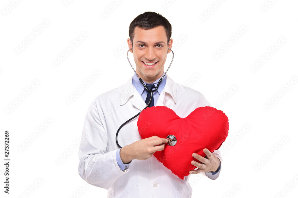 A smiling doctor examining a red heart shaped pillow A smiling doctor examining a red heart shaped pillow