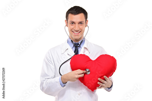 A smiling doctor examining a red heart shaped pillow