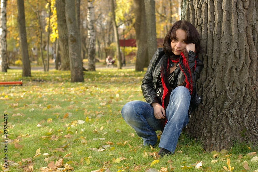 Girl sitting under the tree in an autumn park Girl sitting under the tree in an autumn park