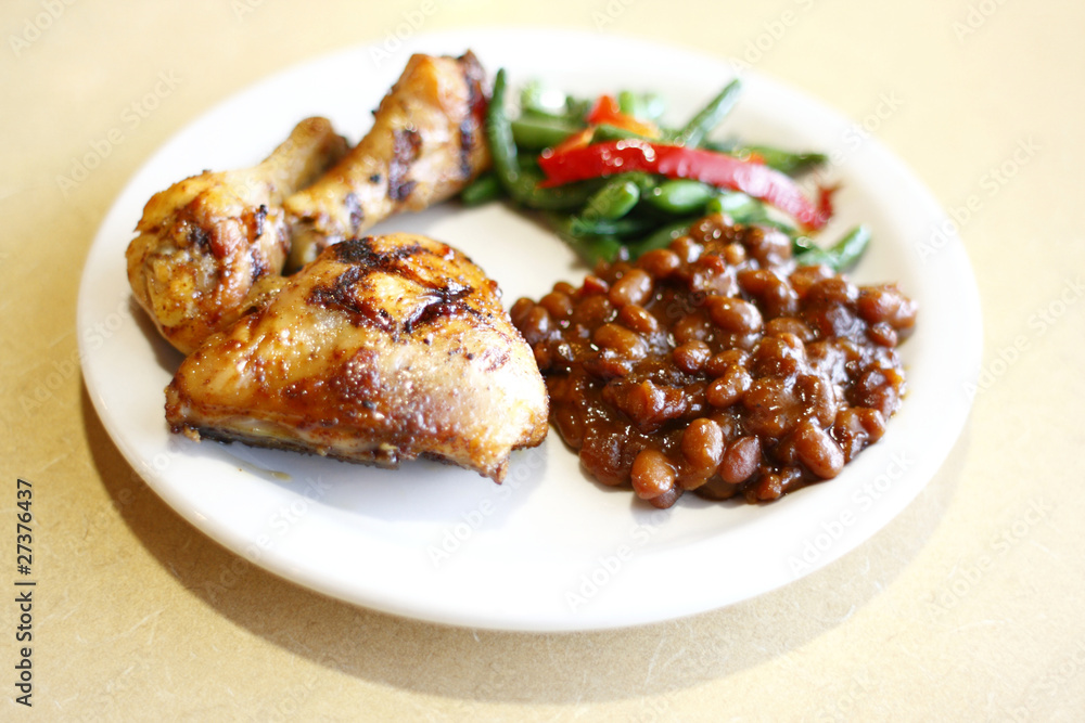 Baked chicken with a side of baked beans and peas Baked chicken with a side of baked beans and peas