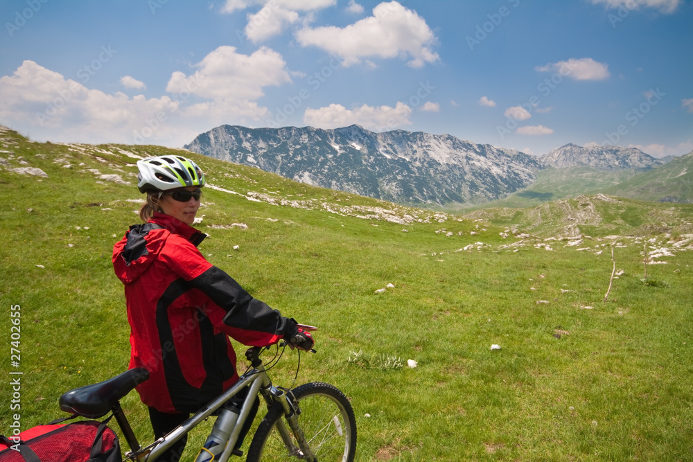 Woman with mountain bike on Alpinean green valley
