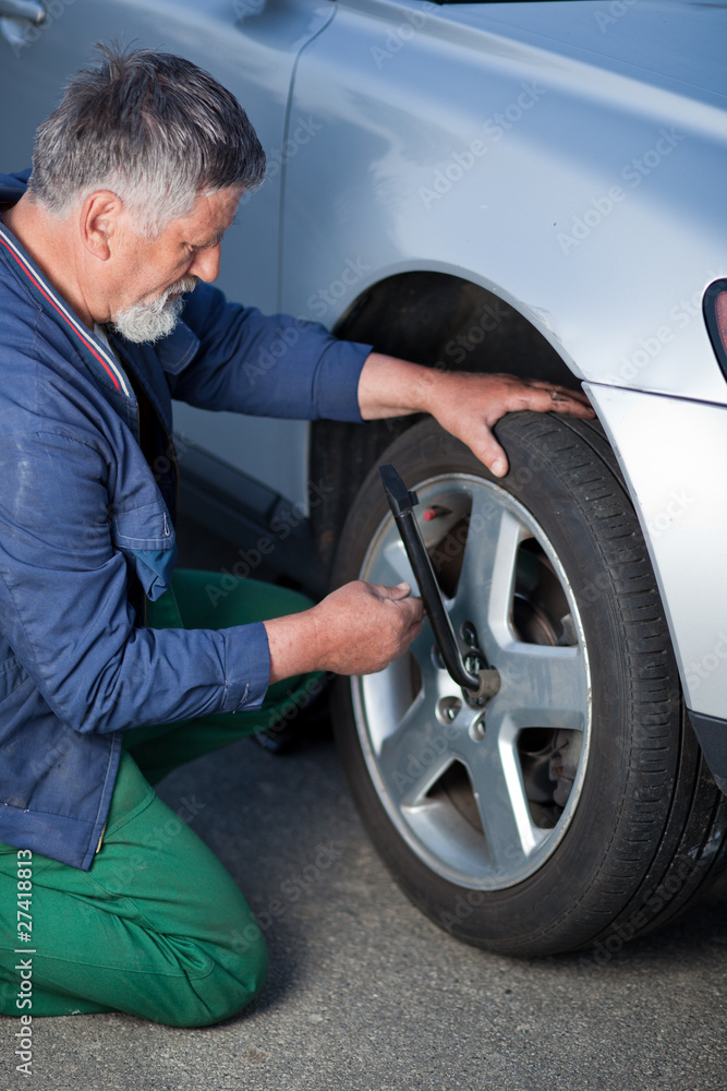 mechanic changing a wheel of a modern car (shallow DOF; color to mechanic changing a wheel of a modern car (shallow DOF; color to
