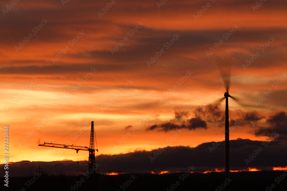 Obraz premium Windrad und Baukran bei Sonnenuntergang