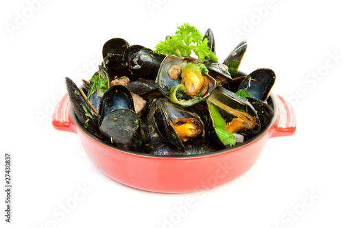 cooked mussels in red casserole over white background