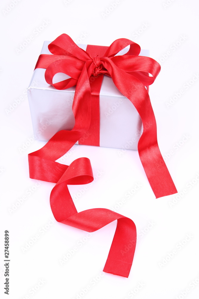 Gift in silver wrapping with a red bow on white background Gift in silver wrapping with a red bow on white background