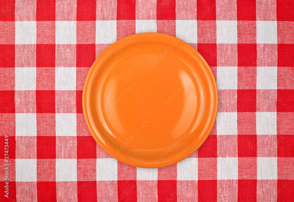 orange plate on red checked tablecloth orange plate on red checked tablecloth