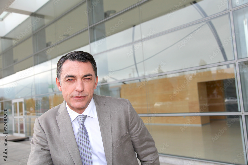 Businessman standing outside modern building Businessman standing outside modern building