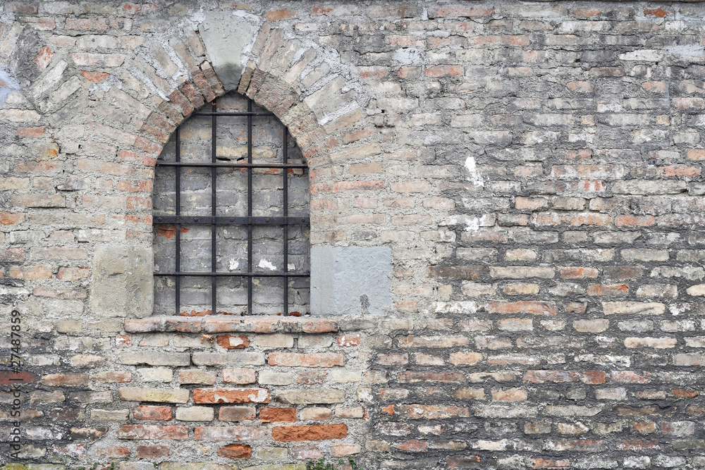 Mauer aus Steinen mit Fenster und Gitter