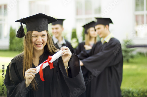 A graduate holding a diploma and smiling