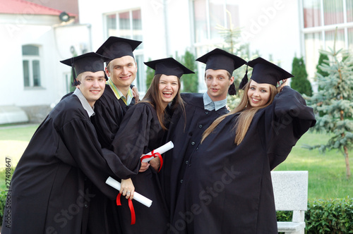 Graduates embrace, enjoy and look at the camera