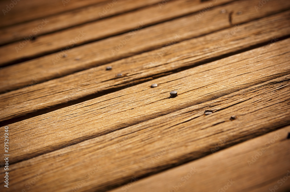 Old wooden decking in need of repair work with cracks and loose nails Old wooden decking in need of repair work with cracks and loose nails