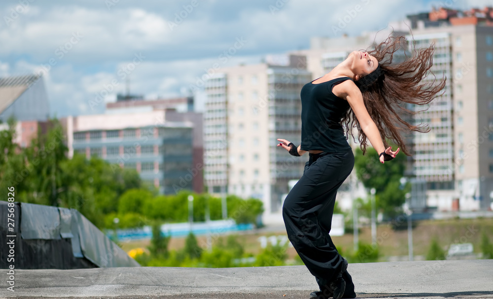 Beautiful girl dancing hip-hop over urban landscape