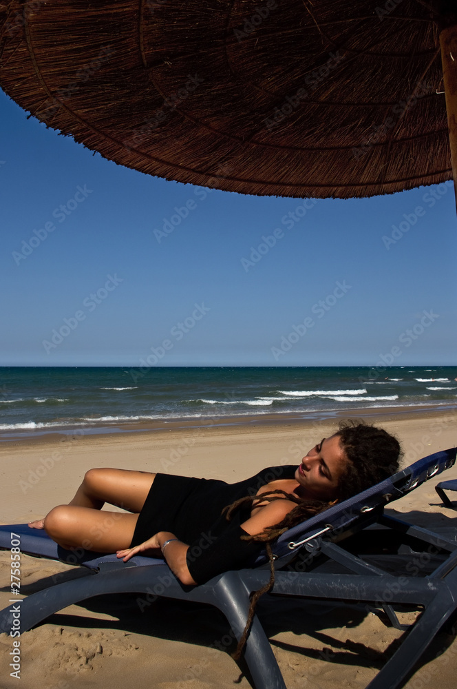 Girl in black dress resting on the beach