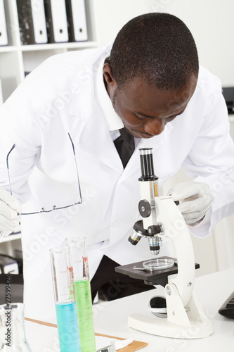 african male scientist looking through microscope