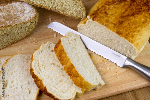 A loaf of homemade bread on a breadboard with a breadknife photo