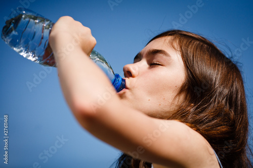 Girl drinking water against blue sky
