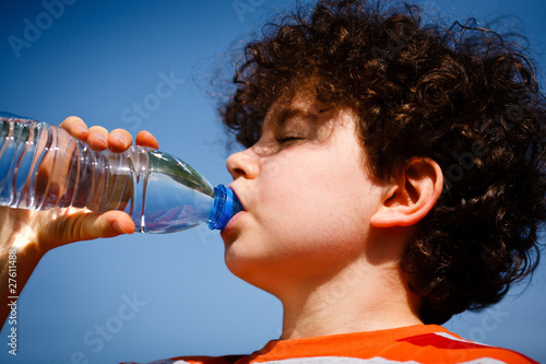 Boy drinking water against blue sky