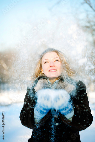 Happy friendly woman blowing snowflakes