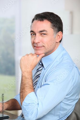 Businessman sitting at his desk with hand on chin