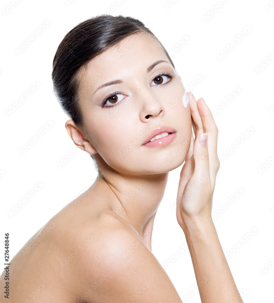 Beautiful woman applying cosmetic cream on face