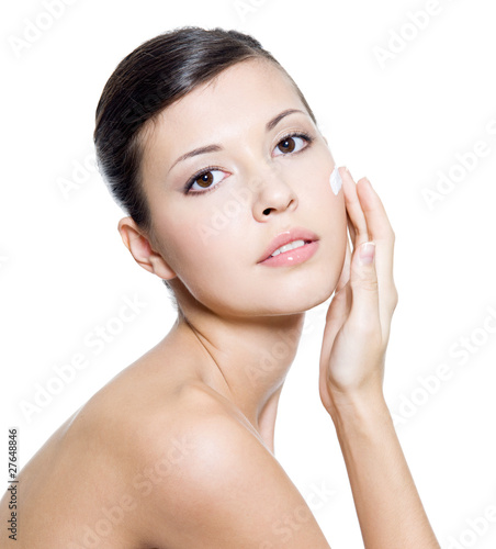 Beautiful woman applying cosmetic cream on face