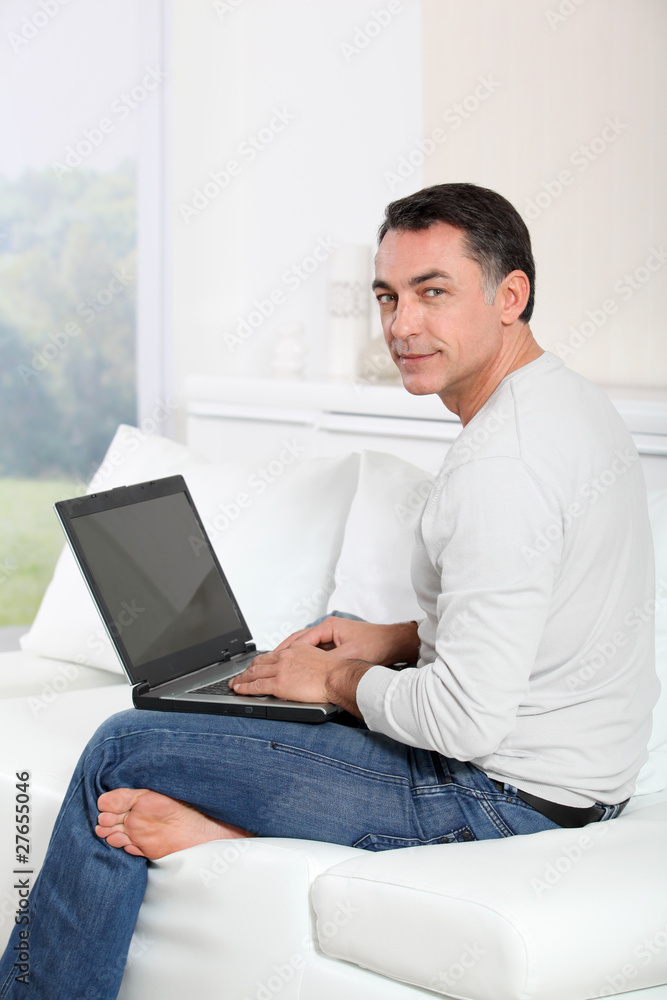 Man sitting on sofa at home with laptop computer