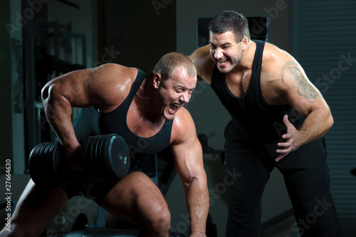 Two bodybuilders training in gym