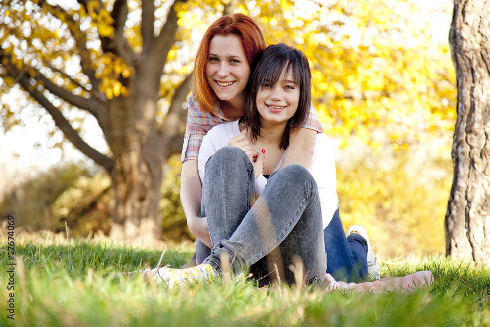 Two beautiful girlfriends at the autumn park near tree. Two beautiful girlfriends at the autumn park near tree.