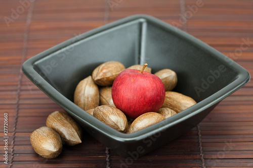 pecans and apples in a bowl on a bamboo mat