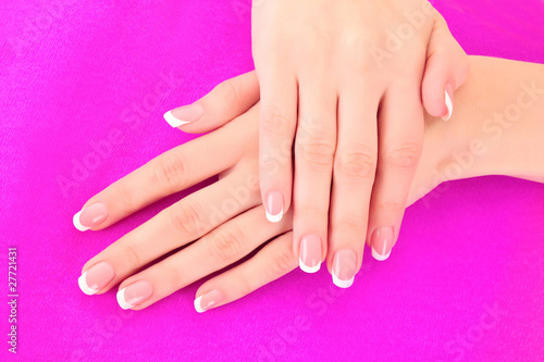 Beautiful woman hand with french manicure on pink background