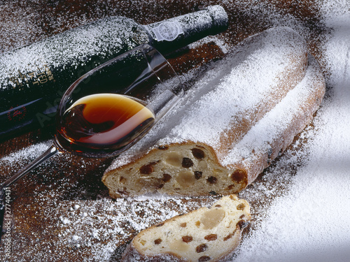 glass of wine and a stollen with powdered sugar and a bottle