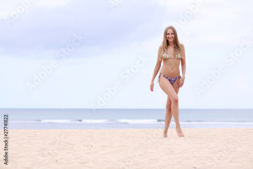 happy woman in bikini walks on a beach