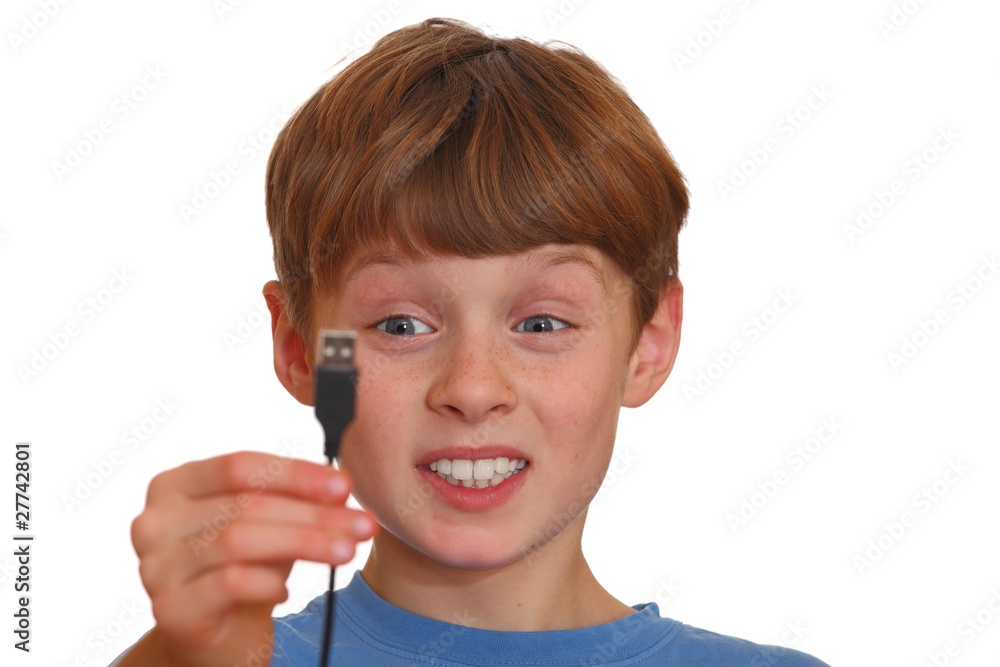 Verwirrter Junge schaut auf einen USB-Stecker Verwirrter Junge schaut auf einen USB-Stecker