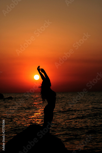 Female silhouette on sunset background