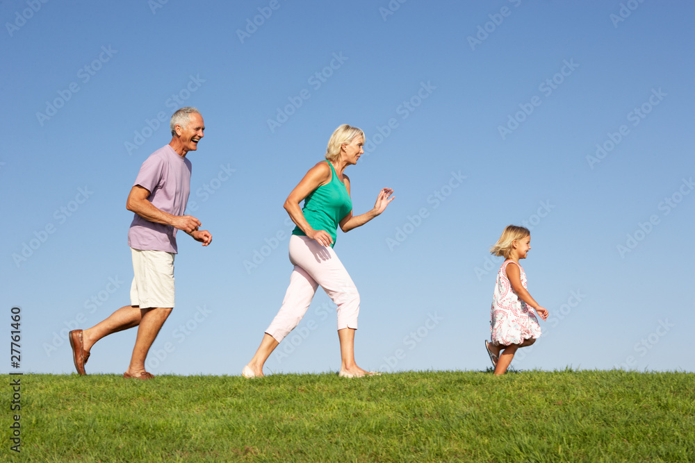Senior couple, with granddaughter,  running through field