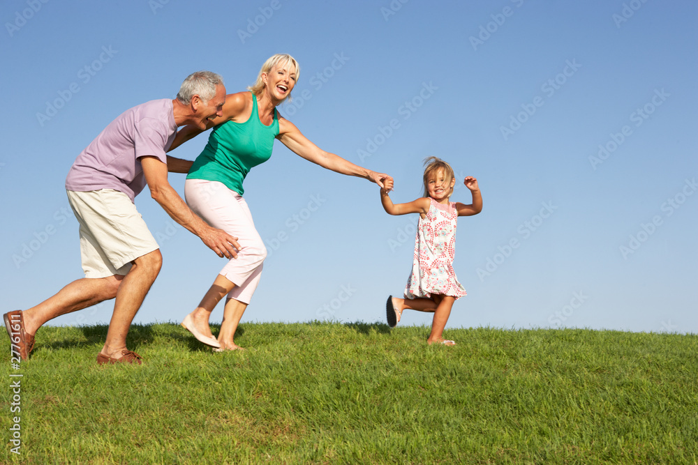 Senior couple, with granddaughter, running through field Senior couple, with granddaughter, running through field