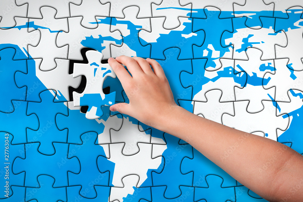 Child's hand inserting piece of jigsaw puzzle into the map hole Child's hand inserting piece of jigsaw puzzle into the map hole