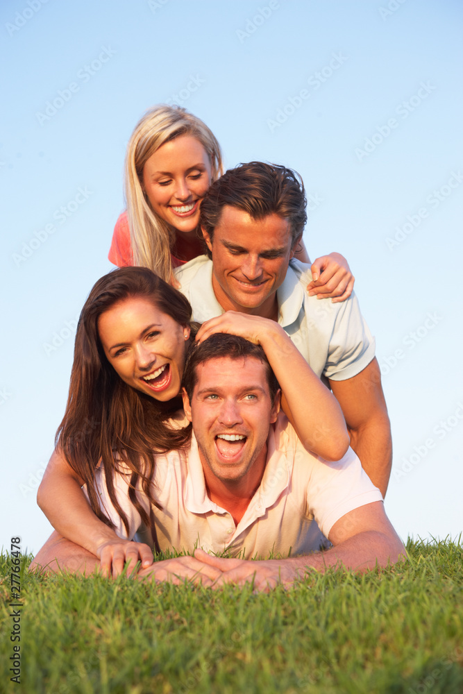 Two, young couples posing on a field Two, young couples posing on a field