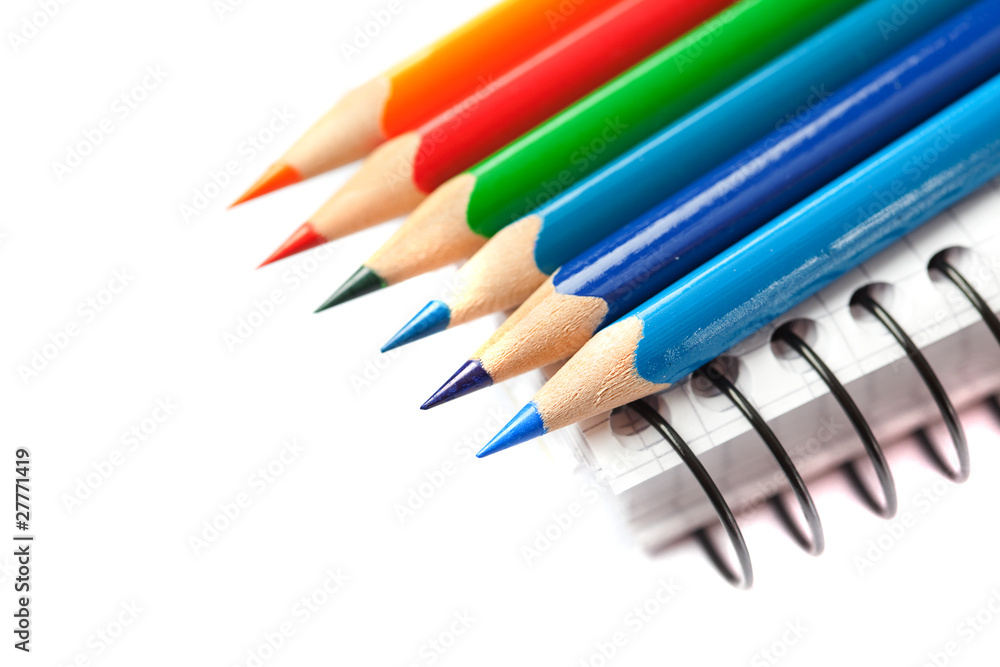 colored pencils and a notebook isolated on white