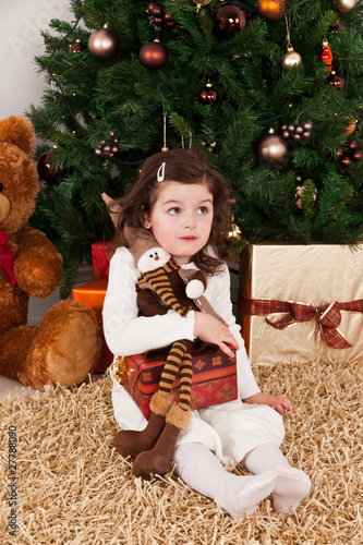 Wondering little girl in a front of Christmas-tree